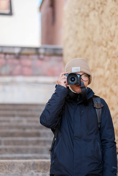 Mladý muž cestovatel se svetrem a batohem cestování v chrámu Songzanlin, šťastný fotograf fotografování na výlet Zhongdian města (Shangri-La) Yunnan, Čína. Asie a Solo cestovní koncept - Fotografie, Obrázek