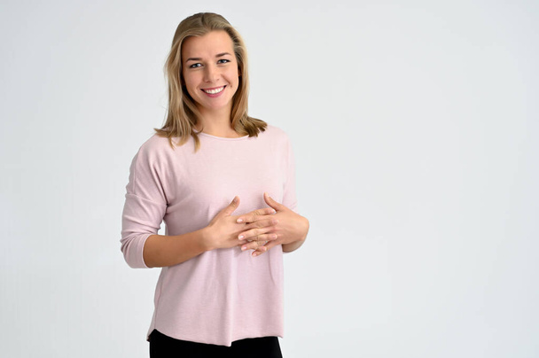 Close-up portrait of a cute caucasian blonde female student girl in pink blouse on a white background. Wide smile, happiness. It is in different poses. - Photo, Image