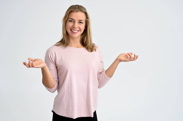 Retrato de cerca de una linda estudiante rubia caucásica en blusa rosa sobre un fondo blanco. Amplia sonrisa, felicidad. Está en diferentes posturas
. - Foto, imagen