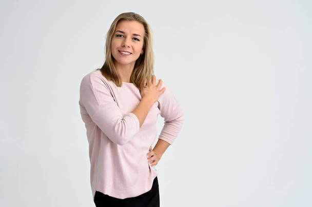 Close-up portrait of a cute caucasian blonde female student girl in pink blouse on a white background. Wide smile, happiness. It is in different poses. - Fotoğraf, Görsel
