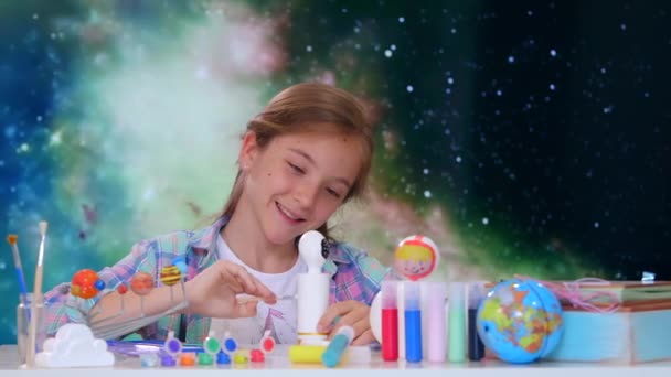 Маленька дівчинка малює рухомий колір тла космосу. Дитина сидить на своєму домашньому столі і бути творчою
. - Кадри, відео