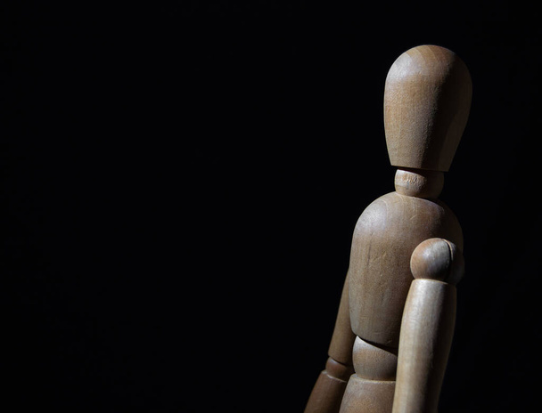 a wooden toy stands on a black background - Foto, Bild
