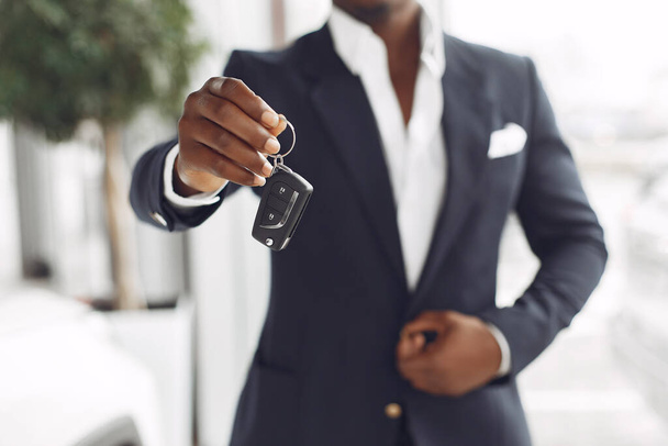 Handsome and elegant black man in a car salon - Foto, Imagen