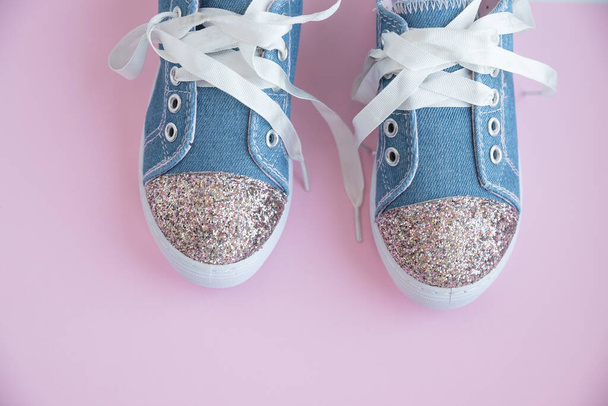 Μοντέρνα μπλε αθλητικά παπούτσια για κορίτσια απομονωμένα σε ροζ φόντο. Ζεύγος trendy παιδικών αθλητικών παπουτσιών Trandy denim sneakers για παιδιά.Ζεύγος trendy γυαλιστερών sneakers, με λευκά κορδόνια. Στυλ νεολαίας - Φωτογραφία, εικόνα