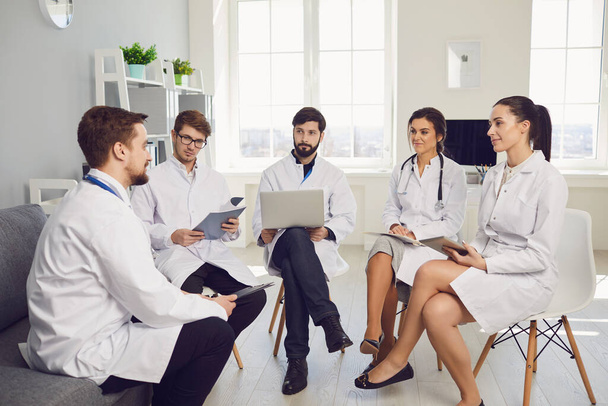 Group of practicing doctors in a meeting discuss the diagnosis of a patient standing in a clinic office. - Foto, Imagem