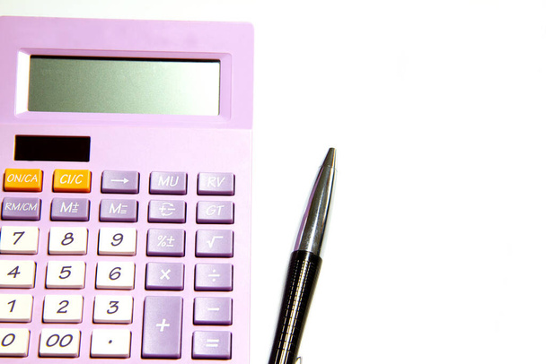 Paarse rekenmachine en pen op een witte achtergrond - Foto, afbeelding