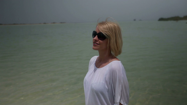 νεαρή γυναίκα με γυαλιά ηλίου στην παραλία - Πλάνα, βίντεο