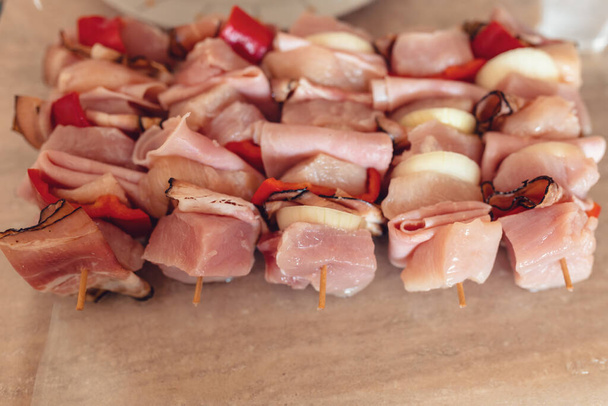 rohes Fleisch, Huhn, Speck, Schweinefleisch, Zwiebeln und scharfe Gewürze auf Spießen bereit für den Grill. - Foto, Bild