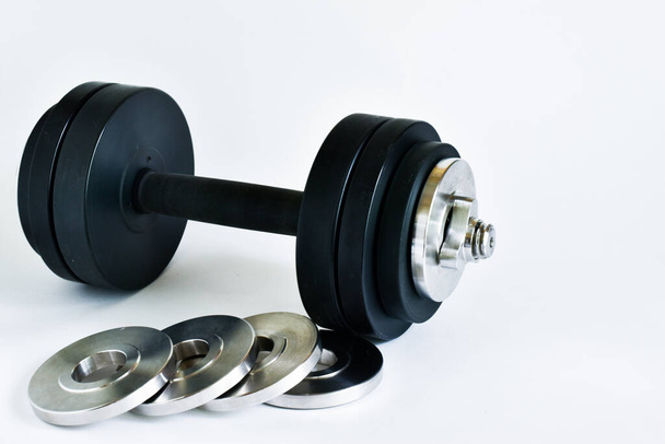 big black dumbbell and wheels for weight gain on a white background, playing sports at home in the gym. view from the side. place for text - Фото, зображення