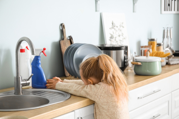 Little girl trying to reach out for bottles of detergent at home - Foto, immagini