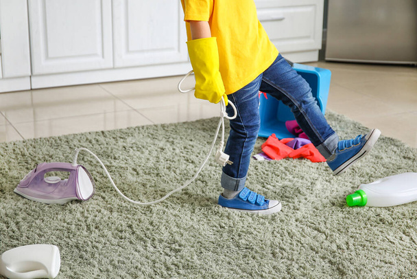 Küçük çocuk evde temizlik malzemeleri ve ütüyle oynuyor. - Fotoğraf, Görsel
