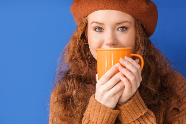 Hermosa mujer joven con taza de cacao caliente sobre fondo de color - Foto, Imagen