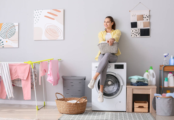 Young woman doing laundry in bathroom - Фото, изображение