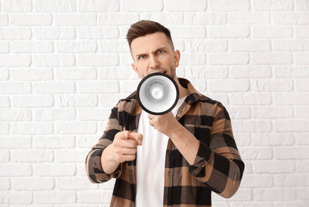 Emotional young man with megaphone on white background - Фото, зображення