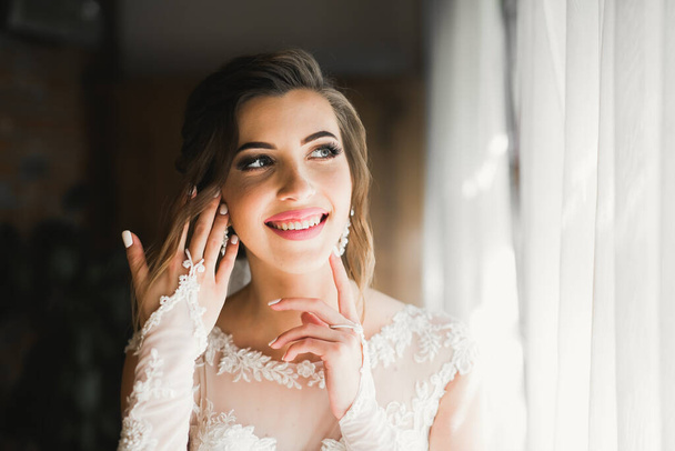 Gorgeous bride in robe posing and preparing for the wedding ceremony face in a room - Fotografie, Obrázek