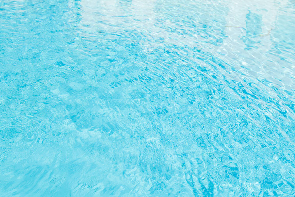Pozadí vodní hladiny. Modrá voda s odlesky slunce. Vlnky vody v bazénu. - Fotografie, Obrázek