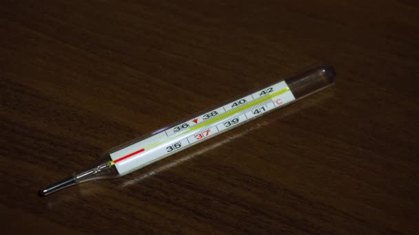 Thermometer van medisch glas op tafel met behulp van animatie toont een stijgende temperatuur tot 39 C tijdens de wereldwijde epidemie van het dodenvirus - Video