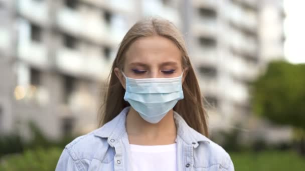 Pandemic team .Long hair  young woman stay in medical mask on city street.  - Кадры, видео