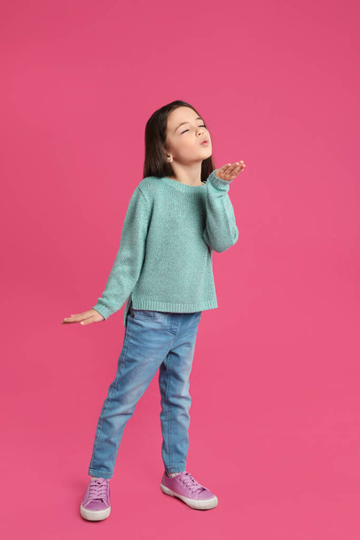 Cute little girl blowing air kiss on pink background - Foto, afbeelding
