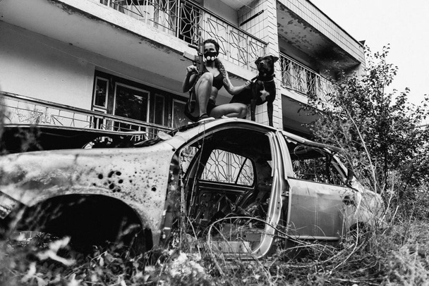 Post apocalypse. A girl is standing in a car and holding a dog on a leash. - Foto, immagini