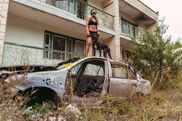 Post apocalypse. A girl is standing in a car and holding a dog on a leash. - Foto, imagen