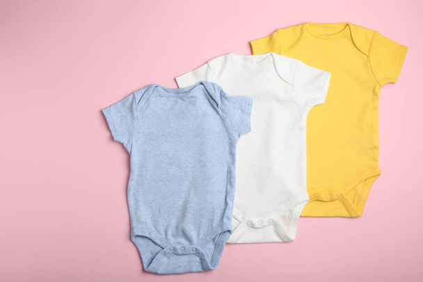 Child's bodysuits on pink background, flat lay - Foto, afbeelding
