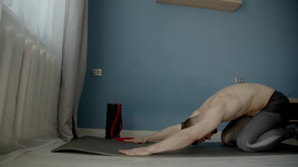 muscle guy doing stretching on a floor in a living room  - Séquence, vidéo