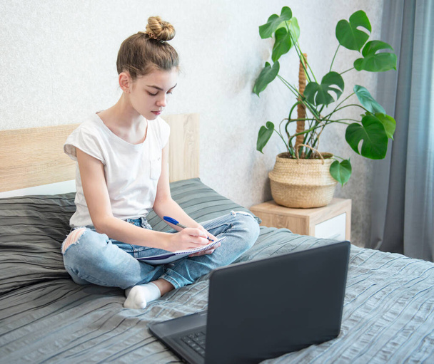 Liseli kız evde dizüstü bilgisayar kullanarak ders çalışıyor. Evde kal. Çevrimiçi eğitim, ev eğitimi, karantina kavramı. - Fotoğraf, Görsel