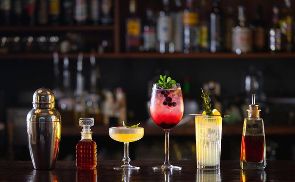 several different cocktails, shaker and bitters on the bar - 写真・画像
