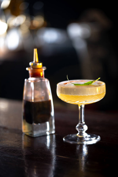 Sidecar cocktail standing on the bar. Night club scenery. - Фото, изображение
