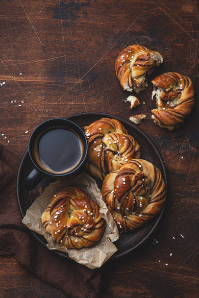 Kanelbullar, swedish cinnamon and cardamon buns, wooden background, top view - Fotoğraf, Görsel