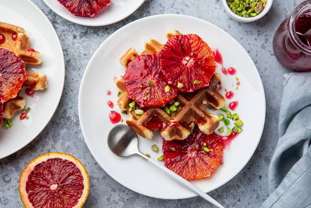 sweet waffles with red blood oranges and pistachios nuts, concrete background, top view - Φωτογραφία, εικόνα