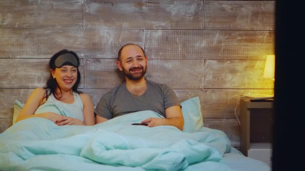 Amused couple watching TV in bedroom - Footage, Video