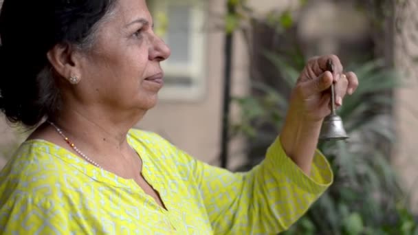 Mujer india de la tercera edad tocando la campana del templo como una señal de respeto a los trabajadores sanitarios esenciales, personal médico, médicos, policías y más durante el cierre del coronavirus en la India
 - Imágenes, Vídeo