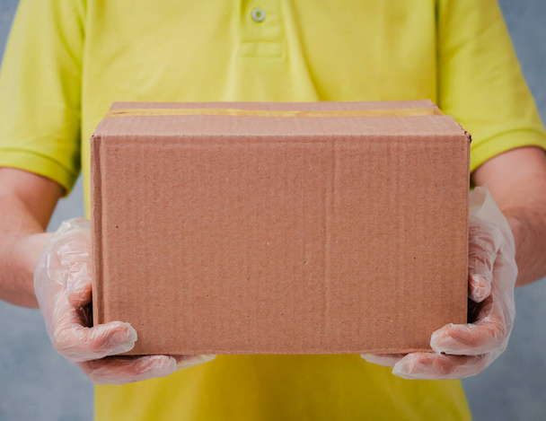 El mensajero sostiene cajas de cartón en guantes desechables. Entrega sin contacto durante el período de cuarentena del coronavirus
 - Foto, imagen