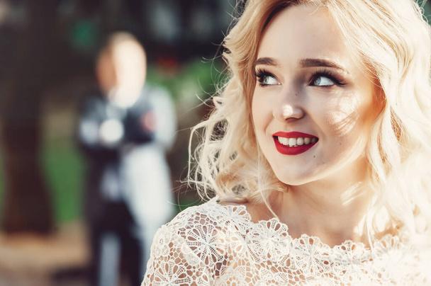 Close-up Retrato de bela feliz Smilling Curly Blond Hair Bride. Vestido de moda e maquiagem com lábios vermelhos
. - Foto, Imagem