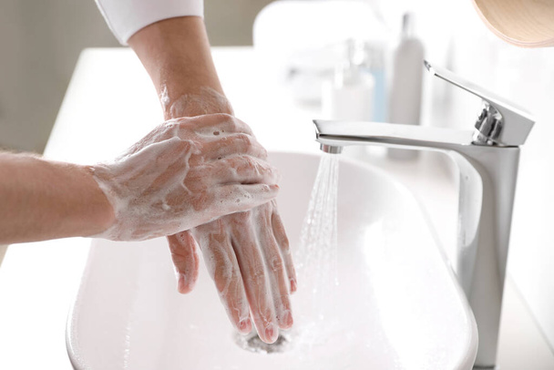 Man washing hands with soap over sink in bathroom, closeup - Fotoğraf, Görsel