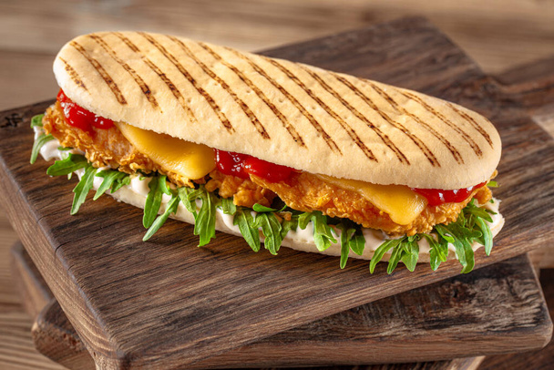 パニーニ・サンドイッチにクリスピーチキンとルコラサラダ - 写真・画像