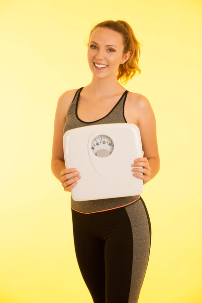 Beautiful young active fit woman hold scale as gesture of loosing weight isolated over white background - weight loss . - Φωτογραφία, εικόνα