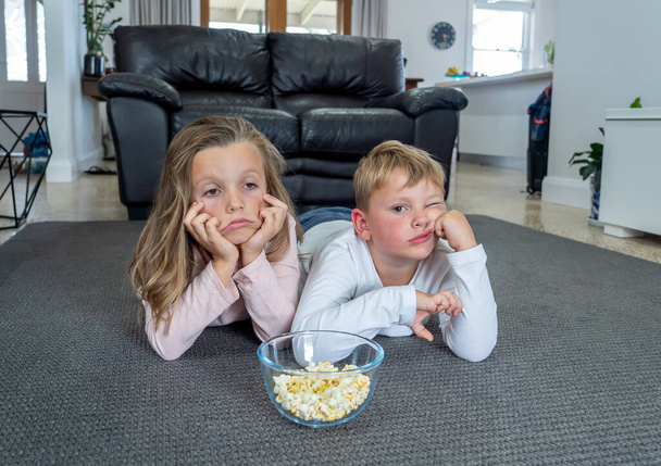 Coronavirus lockdow. Bored little girl and sad boy watching tv in isolation at home during quarantine COVID 19 Outbreak. Mandatory lockdowns and school closures impact on children mental health. - Photo, image