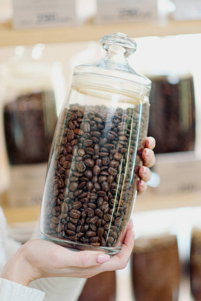A young blonde woman chooses cereal coffee in the store. Tests different varieties of coffee from a jar. - Fotó, kép