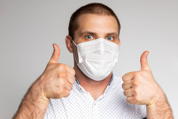 Male office worker in polo shirt, medical mask  on a white isolated background. Concept photo: worker is afraid of news about coronovirus and believes in positive - Photo, Image