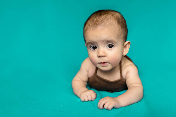 Neugeborenes Baby. Ein kleiner Junge im braunen Body. Schönes Porträt eines Kleinkindes. Großäugiges Baby.  - Foto, Bild