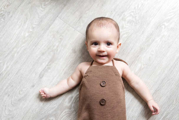 Bebé recién nacido. Un niño pequeño en traje marrón. Hermoso retrato de un niño pequeño. Bebé de ojos grandes
.  - Foto, Imagen