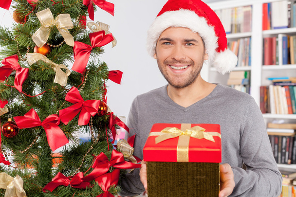 Man holding a gift box near the Christmas tree - Fotoğraf, Görsel