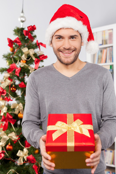 Man holding a gift box near the Christmas tree - Fotoğraf, Görsel