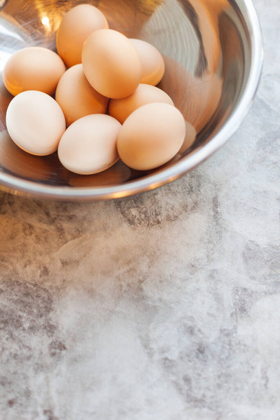 Αυγά κοτόπουλου σε ένα μεταλλικό μπολ στο τραπέζι - Φωτογραφία, εικόνα