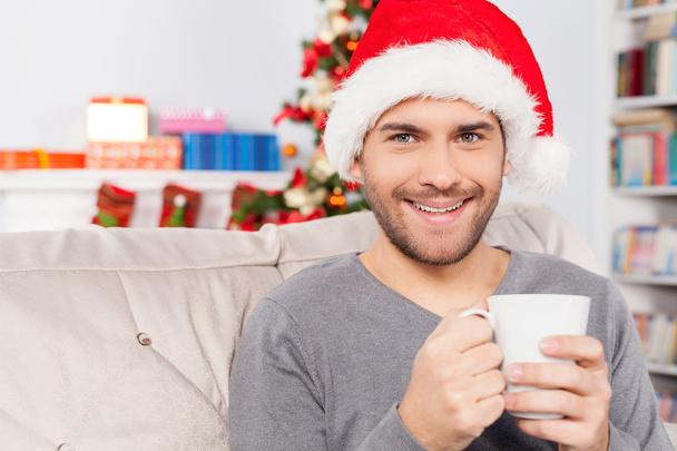 Man in Christmas hat holding a cup and smiling - Fotoğraf, Görsel
