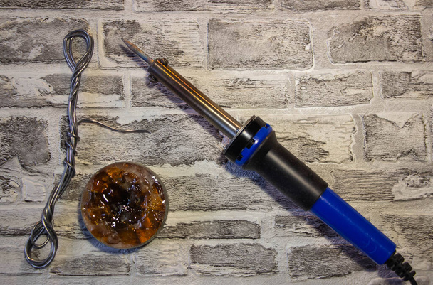 Паяльник з синьою ручкою, ручкою, ручкою і паяльником на фоні цегляної стіни
 - Фото, зображення