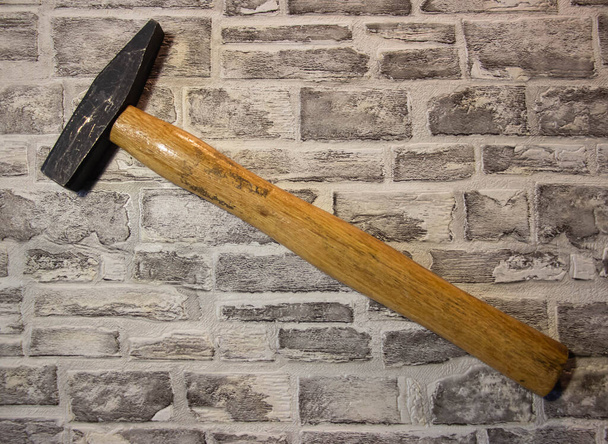 Μαύρο μεταλλικό σφυρί με ξύλινη λαβή σε τούβλο τοίχου backgroun - Φωτογραφία, εικόνα